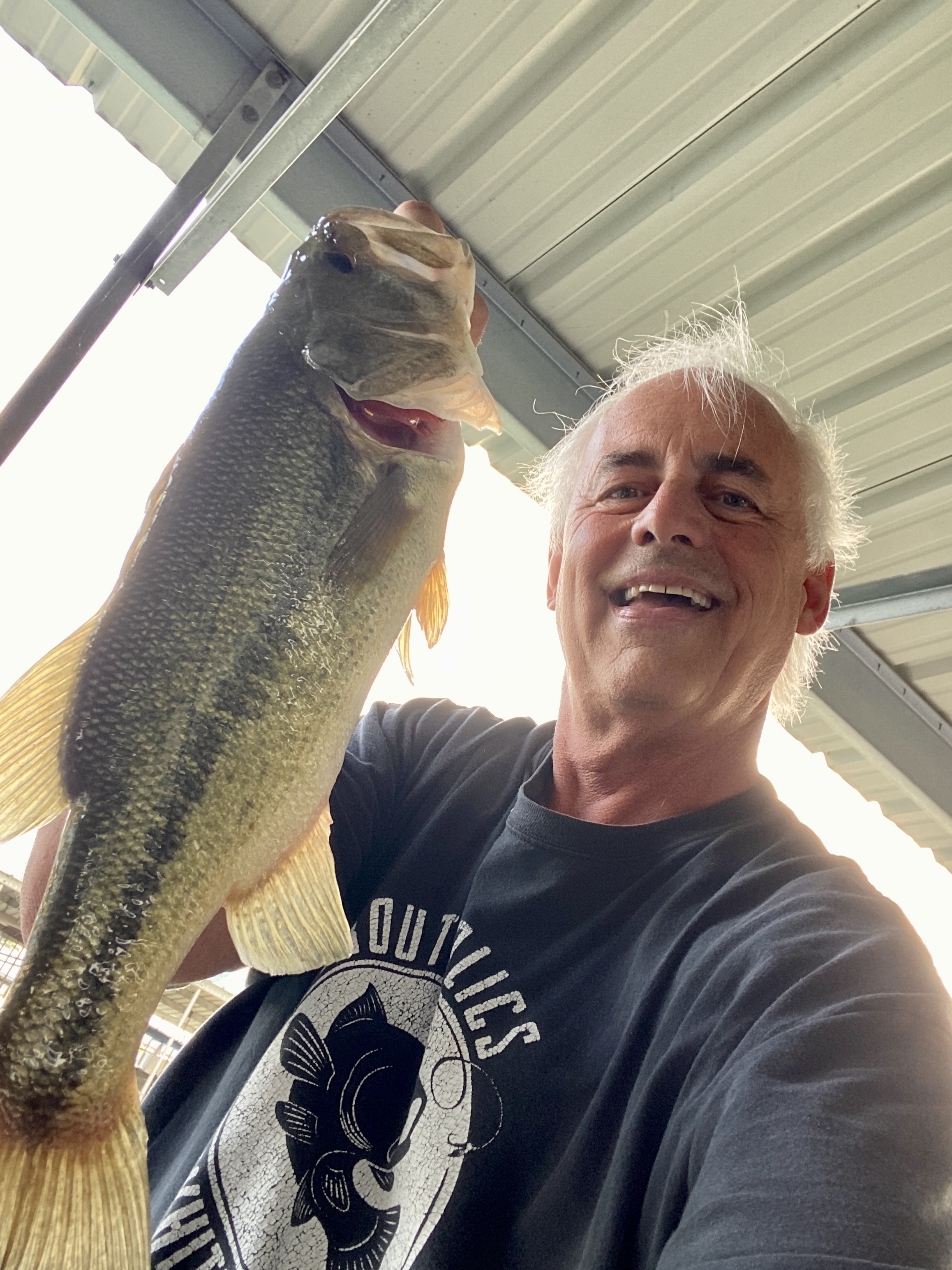 Bill with the five-pounder — biggest bass of the day, pulled from a shaded boat slip.